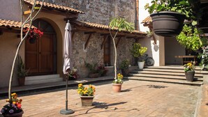 Un patio con plantas en macetas, una puerta de madera y un techo de tejas.