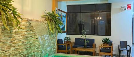 A pool area with a stone wall, seating, and a window.