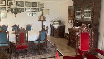 Une salle à manger avec une table et des chaises, un lustre, un buffet contenant de la verrerie et des tableaux encadrés accrochés au mur.