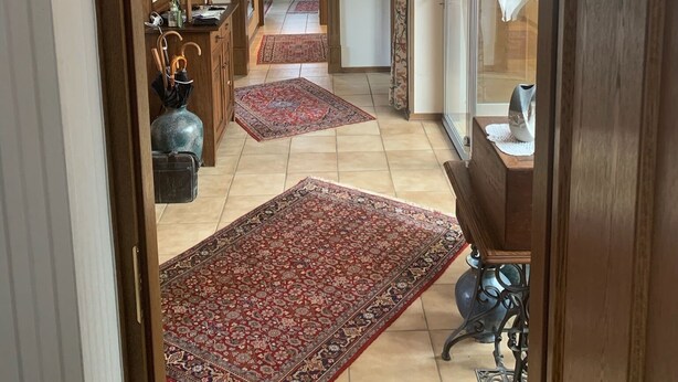 A hallway with a wooden archway, leading to a room with a large rug and a cabinet. - Villa in the middle of Haselünnne (Haselünne)