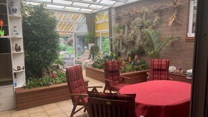 A conservatory with a glass ceiling, wooden furniture, and a variety of plants. - Villa in the middle of Haselünnne (Haselünne)