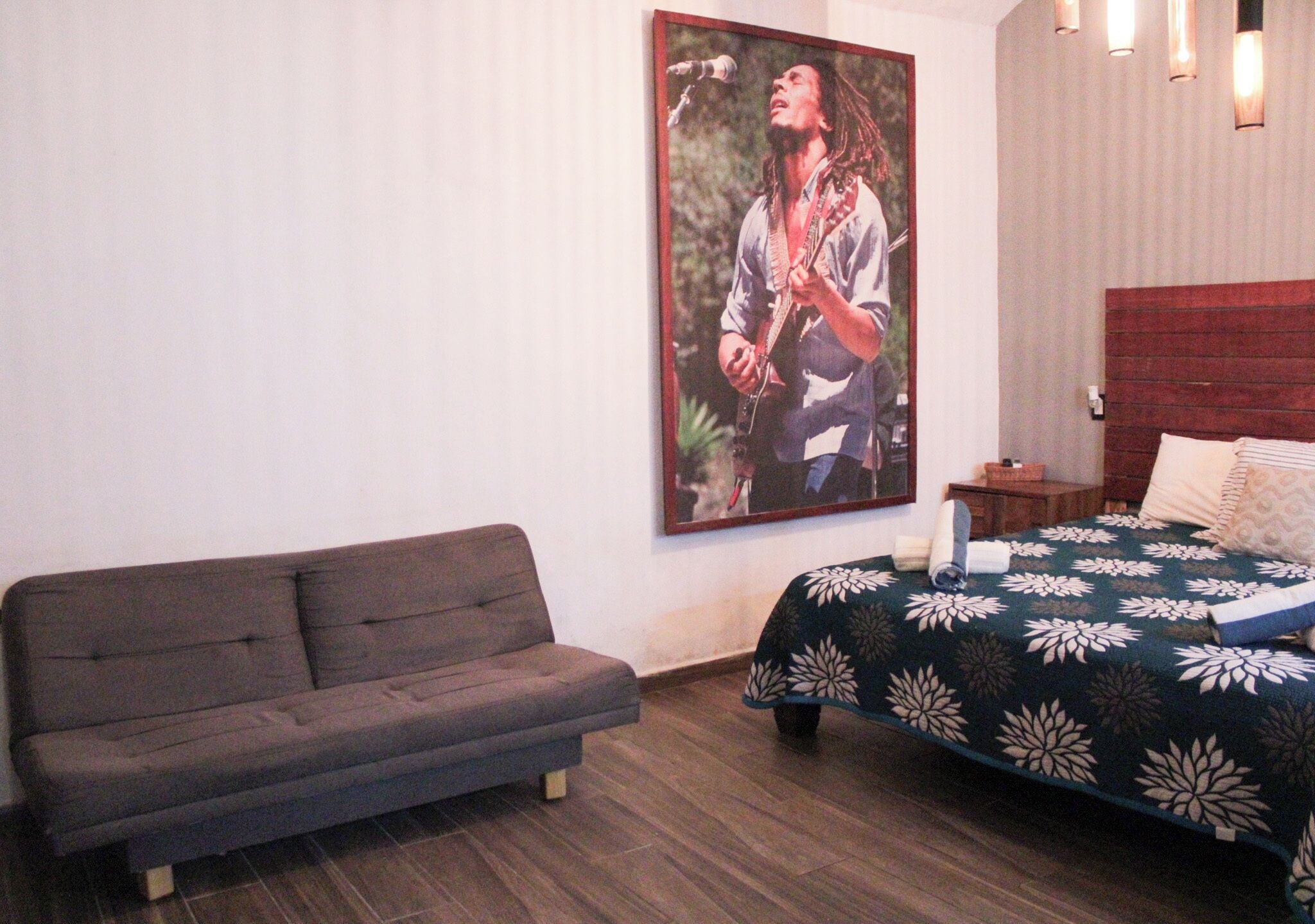 Ein Schlafzimmer mit Bett, einer Couch, einem Bild an der Wand und einem Nachttisch.