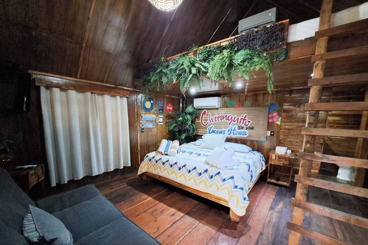 Quarto de madeira com uma cama, um sofá e uma placa que diz 'Chiringuitos Luccas House'.