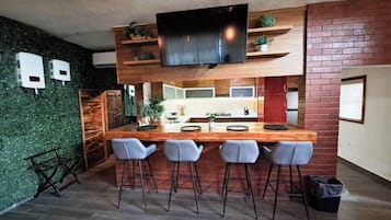 Una cocina moderna con una isla de madera, taburetes de bar y un televisor montado sobre la isla.