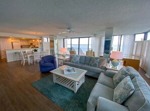 A spacious living area with a sofa, armchairs, a coffee table, and a dining area with chairs and a table.