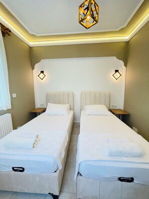 Une chambre d’hôtel avec deux lits, un luminaire au plafond et des lampes fixées au mur.