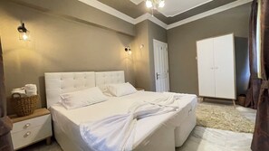 Un dormitorio con una cama grande, mesitas de noche, un armario e iluminación en la pared.