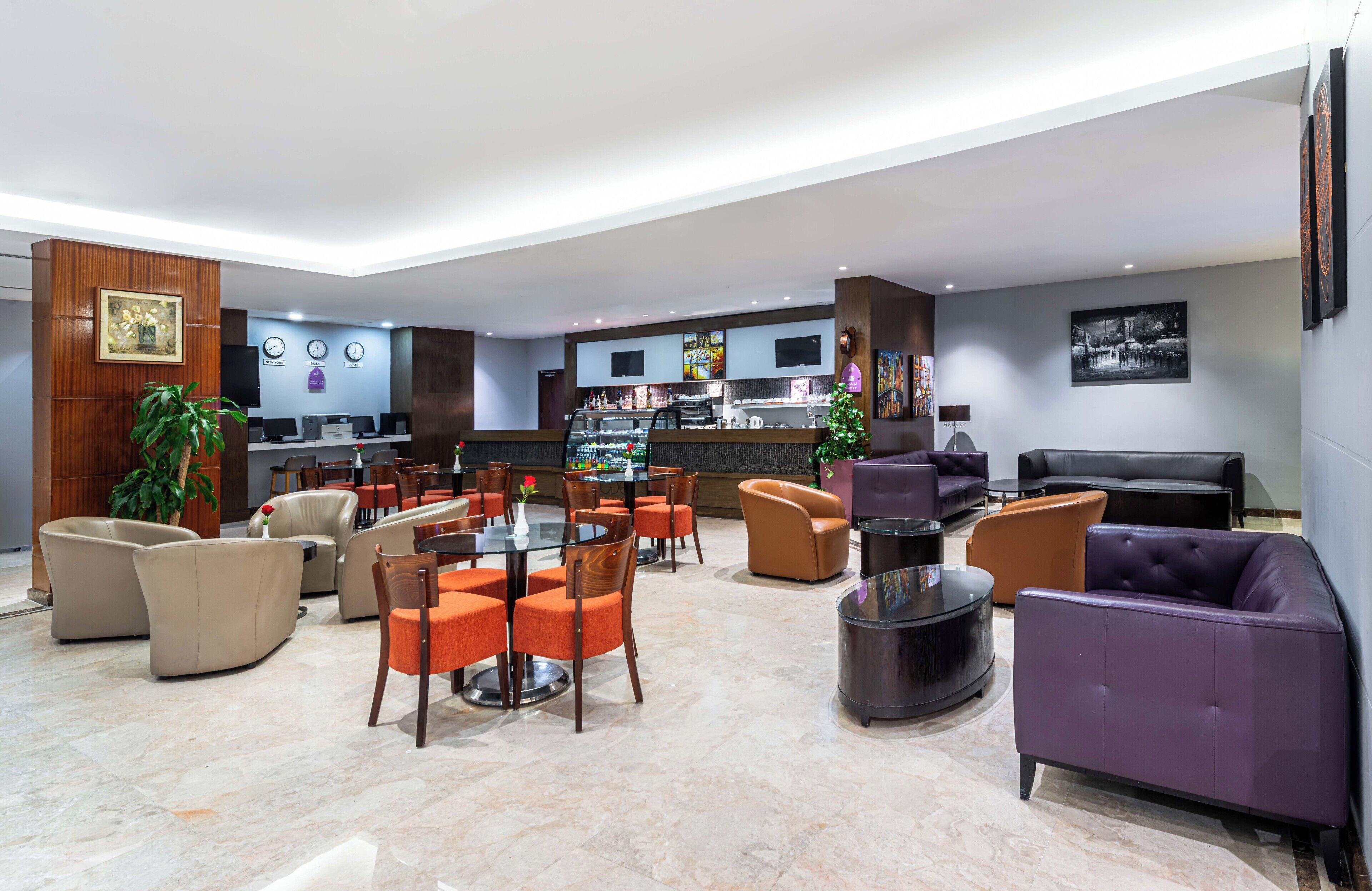 A modern lobby with a bar area, seating arrangements, and a reception desk.
