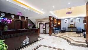 A hotel lobby with a reception desk, seating area, and a staircase. - Razana Al Jubail (Al Jubail)