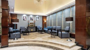 Un hall d’entrée spacieux, doté d’un sol en marbre, d’un lustre et d’un espace détente avec des canapés et des fauteuils.