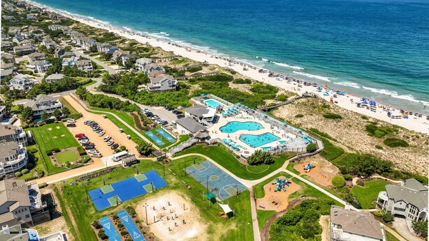 An aerial view of a coastal resort with a large swimming pool, tennis courts, and a beach area. - 1300 - Sea Chest - Corolla Light | Beach Access & Community Amenities (Corolla)