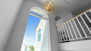 A staircase with white railings and a view of a house through a window. - 1300 - Sea Chest - Corolla Light | Beach Access & Community Amenities (Corolla)