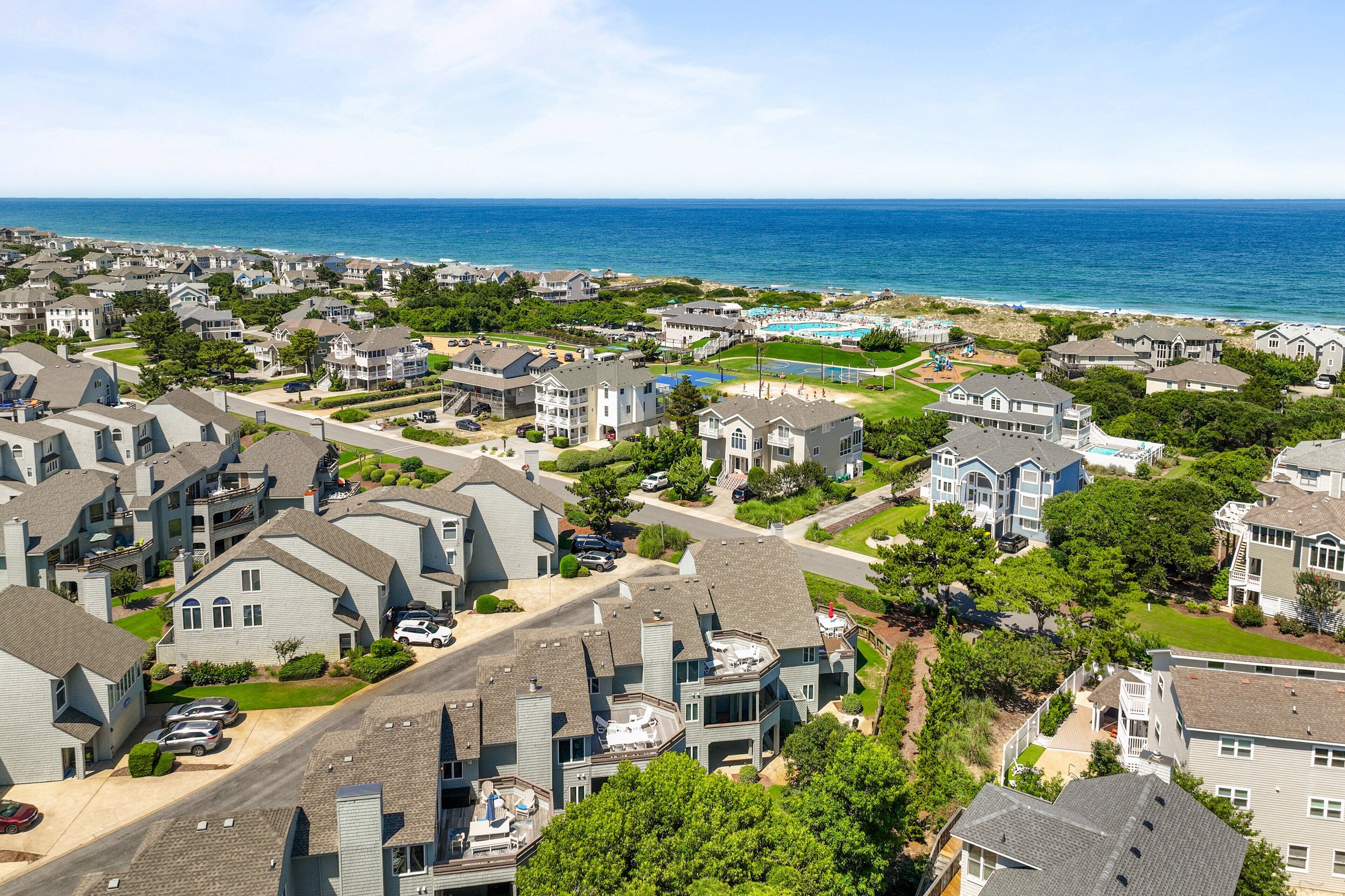 A coastal residential area with houses, a swimming pool, and a view of the ocean.