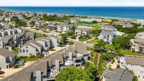 A coastal residential area with houses, a swimming pool, and a view of the ocean. - 1300 - Sea Chest - Corolla Light | Beach Access & Community Amenities (Corolla)