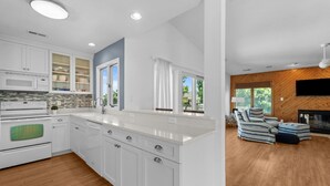 A modern kitchen with white cabinetry, a built-in microwave, and a large island. - 1300 - Sea Chest - Corolla Light | Beach Access & Community Amenities (Corolla)