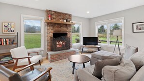 Una sala de estar con chimenea, un sofá, un televisor y una estantería.