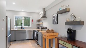 Una cocina moderna con armarios grises, una mesa de madera y una cafetera.