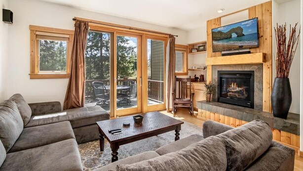 Una sala de estar con chimenea, televisor y puerta corrediza de vidrio que da a un patio.