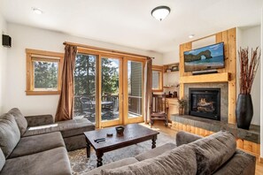 A living room with a fireplace, a television, and a sliding glass door leading to a patio.
