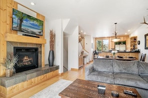 Una sala de estar moderna con chimenea, un sofá gris y un televisor montado en una pared de madera.