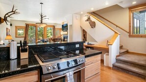 Una cocina con una estufa grande, armarios de madera y un venado montado en la pared.