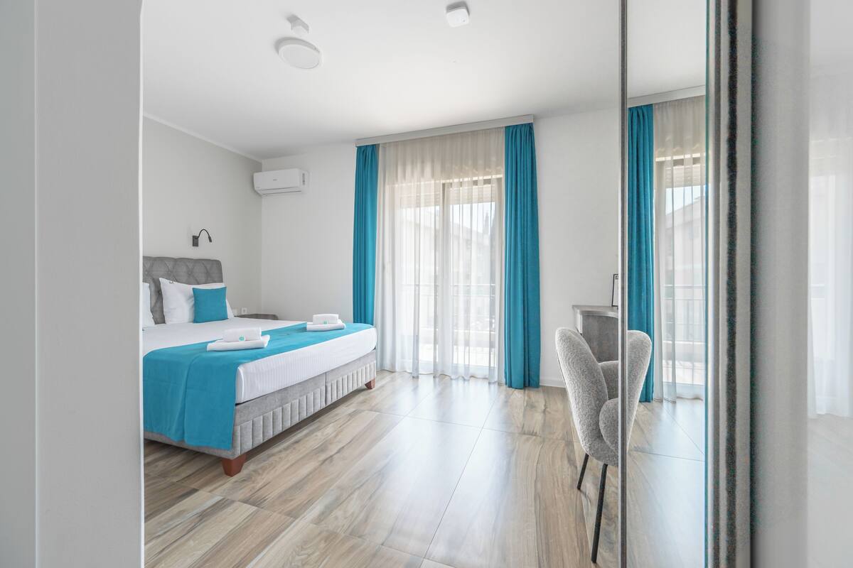 A modern hotel room with a bed, a desk, and a chair.
