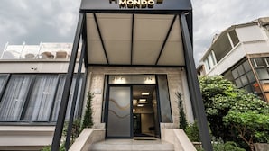 A hotel entrance with a reception desk, a modern sign, and a glass door. - Hotel Mondo  (Budva)