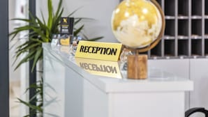 A reception desk with a globe, a clock, and a potted plant. - Hotel Mondo  (Budva)
