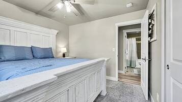 Un dormitorio con una cama grande, un ventilador de techo y una puerta que da a un baño.