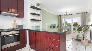 A modern kitchen with dark wooden cabinets, a Bosch oven, and a central island with a sink. - The Sands BG3 - Two Bedroom Apartment, Sleeps 4 (Cape Town)