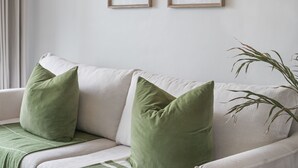 A white sofa with green cushions and a plant beside it. - The Sands BG3 - Two Bedroom Apartment, Sleeps 4 (Cape Town)
