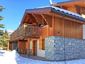 A wooden chalet with a stone foundation, wooden balcony, and a stone wall. - Wifi, 150m from ski lifts, terrace, parking, tv, ski locker, 65m², Les Menuires (Les Menuires)