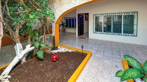A courtyard with a tree, a red ladybug, and a potted plant.