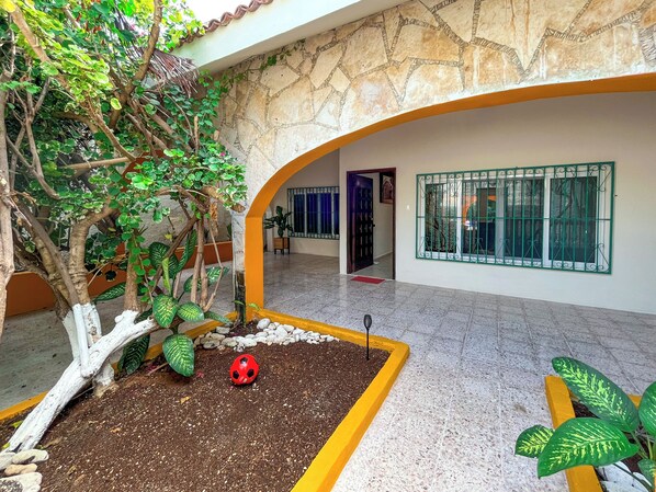 Un patio con un árbol, una mariquita roja y una planta en maceta.