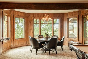 A dining area with a wooden paneled wall, large windows, a chandelier, and a pool table. - Hilltop Luxury with Views, Privacy & Hot Tub, 30-Day Retreat in Gated Community (Heber City)