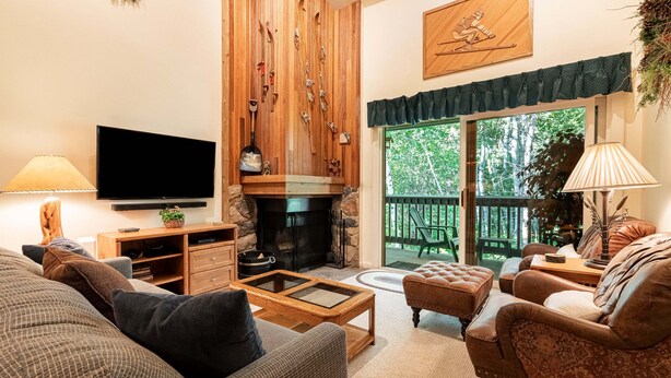 A living room with a fireplace, a television, and a view of the outdoors. - Snowbound at Snow Flower — 2 Bedrooms + Loft, Heated Pool, Hot Tub & Fitness! (Park City)