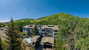A resort with multiple buildings, a swimming pool, and a mountainous backdrop. - Snowbound at Snow Flower — 2 Bedrooms + Loft, Heated Pool, Hot Tub & Fitness! (Park City)