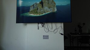 A flat-screen TV mounted on a wall displaying a scenic island landscape.