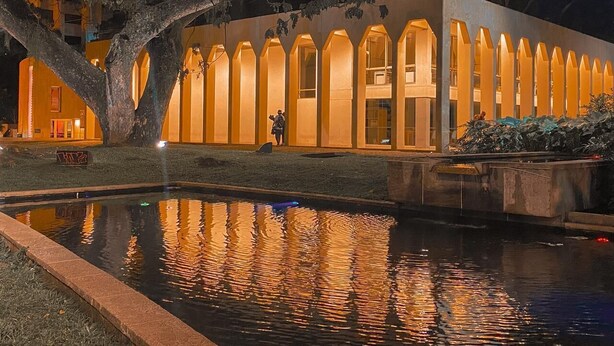 A building with a series of arched windows and a reflective water feature in front.