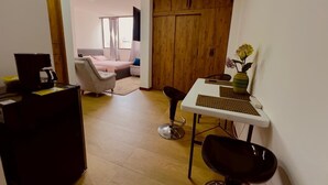 A compact living space with a kitchenette, a dining area with a table and chairs, a sofa, and a large wardrobe.
