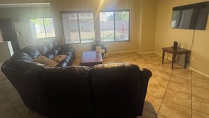 Ein Wohnzimmer mit Ecksofa, einem kleinen Tisch und einem Deckenventilator.