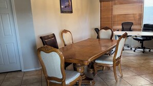 Ein Esszimmer mit Holztisch, gepolsterten Stühlen, einer Chandelieber und einem gerahmten Bild an der Wand.