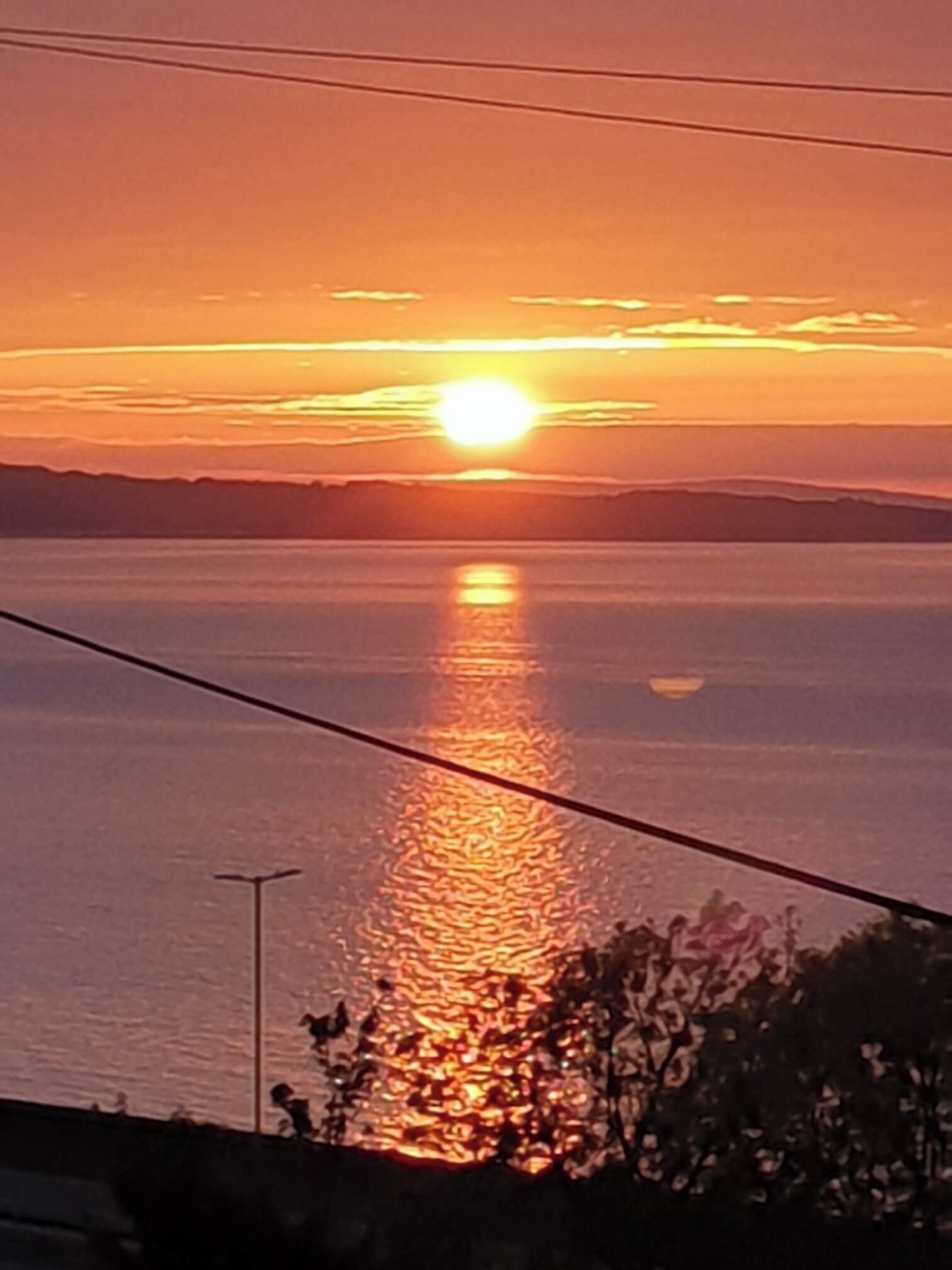 A sunset over a body of water with a clear horizon.