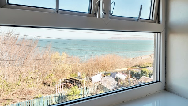 Una ventana con vistas a una masa de agua y una costa lejana.