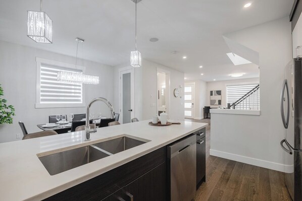 A modern kitchen with a central island, stainless steel appliances, and pendant lighting.