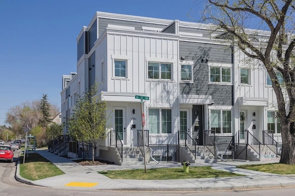 A multi-story residential building with a front entrance, steps, and a street sign.