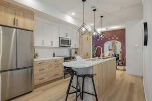 A modern kitchen with stainless steel appliances, wooden cabinets, and a central island with bar stools.