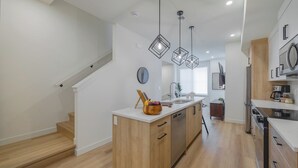 Une cuisine moderne dotée d’un îlot central, de meubles en bois et de luminaires suspendus.
