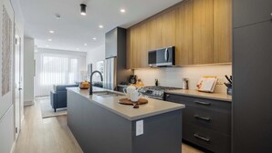 Una cocina moderna con una isla central, muebles oscuros y un microondas sobre la estufa.