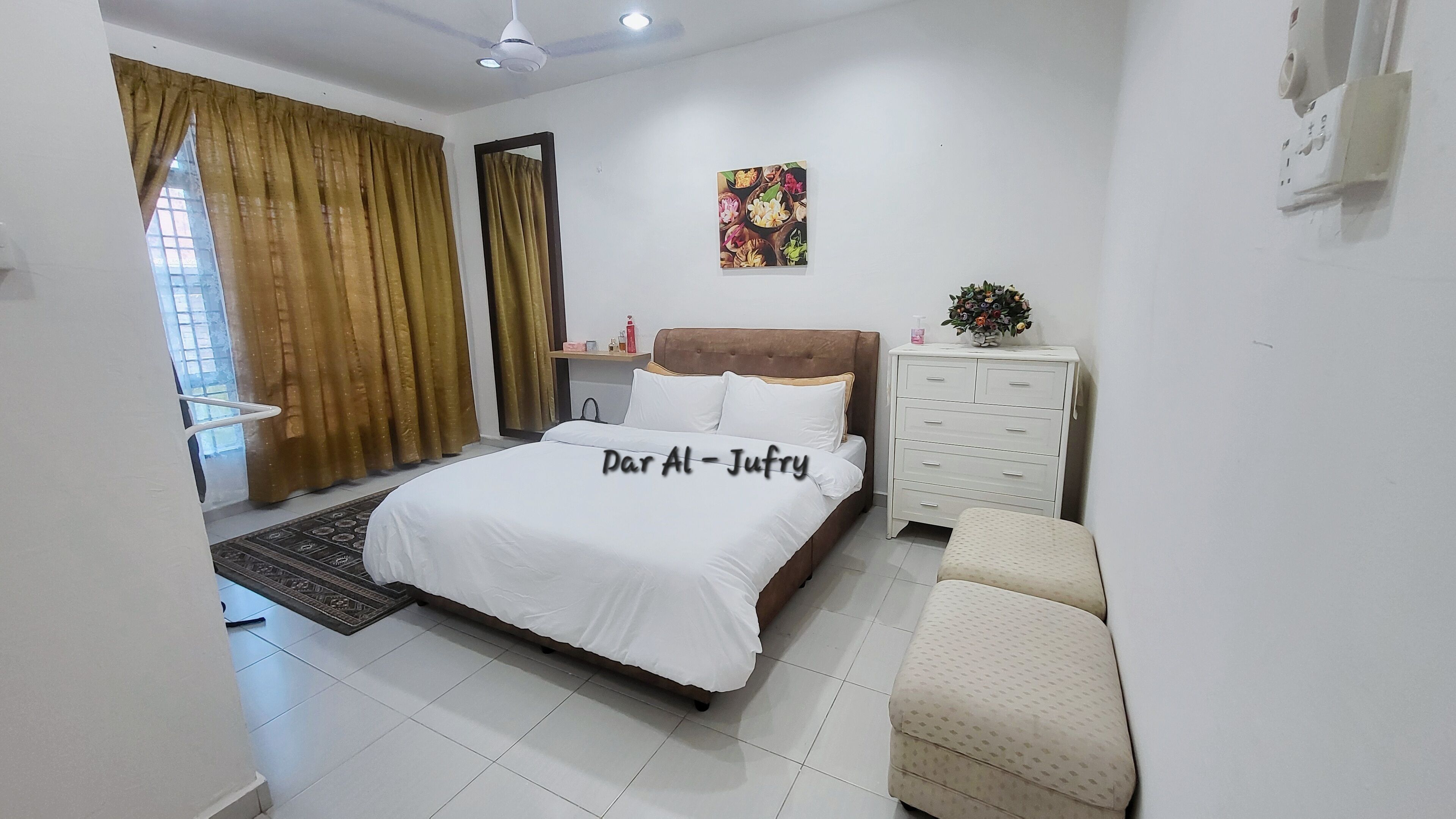 A bedroom with a bed, a nightstand, a dresser, a window with curtains, and a ceiling fan.